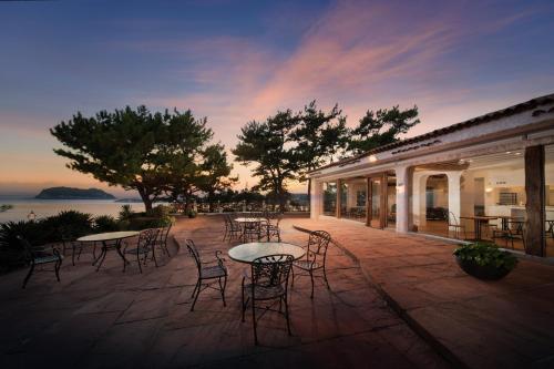 a patio with tables and chairs with a sunset at Seogwipo KAL Hotel in Seogwipo