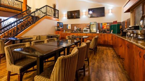 a restaurant with tables and chairs and a staircase at Best Western Plus Sidney Lodge in Sidney