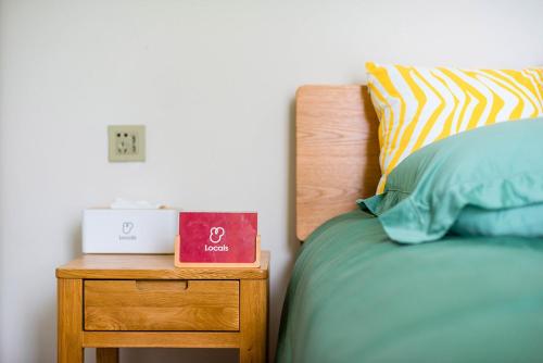 a bed with a nightstand with a alarm clock on it at Henan Luoyang·Chanhe Hui Nationality Area· Locals Apartment 00144150 in Luoyang