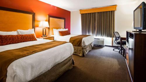 a hotel room with two beds and a flat screen tv at Best Western Plus Sidney Lodge in Sidney