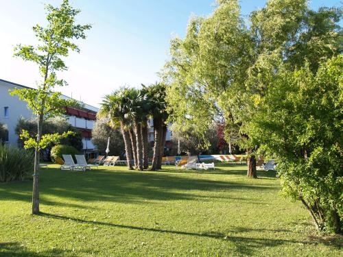 a park with trees and a building in the background at Hotel Giulietta Romeo in Lazise