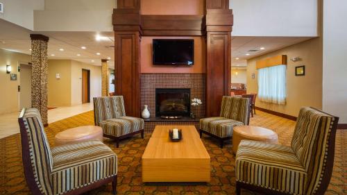 a lobby with a fireplace and chairs and a table at Best Western Plus Finger Lakes Inn & Suites in Cortland