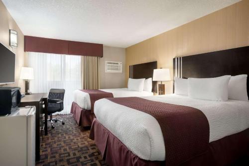 a hotel room with two beds and a desk at Days Inn by Wyndham Sylvan Lake in Sylvan Lake