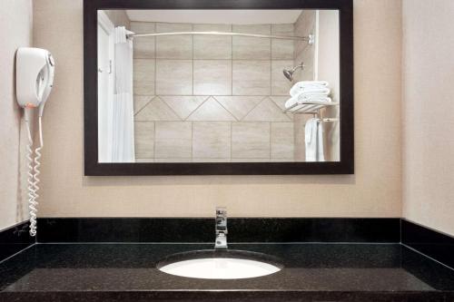 a bathroom with a sink with a phone and a mirror at Days Inn by Wyndham Sylvan Lake in Sylvan Lake