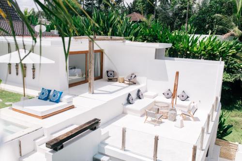 ein weißes Haus mit Stühlen und Pflanzen in der Unterkunft The Apartments Ubud in Ubud