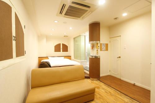 a bedroom with a bed and a couch in a room at Hotel Mio (Adult Only) in Kariya