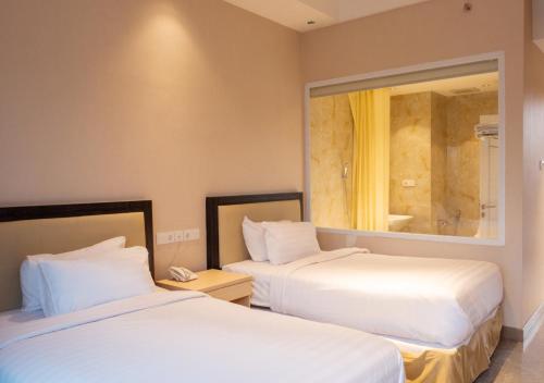 a hotel room with two beds and a mirror at Cahaya Villa Garut in Garut