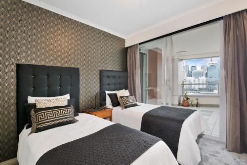 a hotel room with two beds and a balcony at Darling Harbour Getaway in Sydney