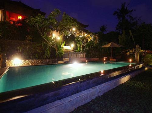a swimming pool lit up at night with lights at Kukuh House Ubud in Ubud