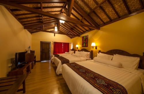 a hotel room with three beds and a television at Puri Sakanti Nature Family Resort in Ciwidey