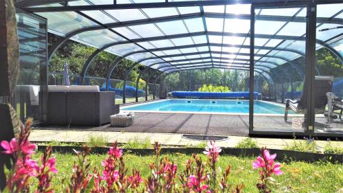 een zwembad met een glazen serre en een zwembadvisor bij Domaine du Plessis Grimaud in Saint-Viaud