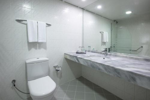 a bathroom with a toilet and a sink and a mirror at The Grand Blue Sky International - All Inclusive in Kusadası