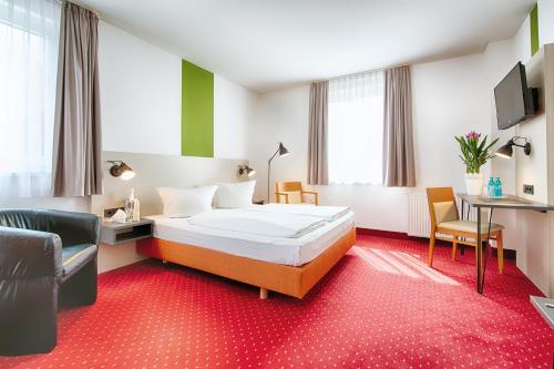 a hotel room with a bed and a chair at ACHAT Hotel Chemnitz in Chemnitz