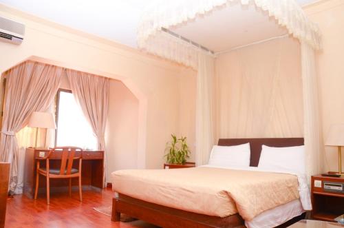 a bedroom with a large bed and a desk at Fang Fang Hotel in Kampala
