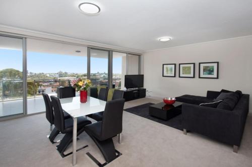 a living room with a table and a couch at The Junction Palais - Modern and Spacious 2BR Bondi Junction Apartment Close to Everything in Sydney