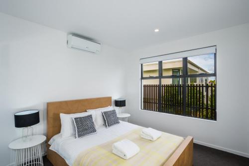a white bedroom with a bed and a window at Oxford Steps - Executive 2BR Bulimba Apartment Across from the Park on Oxford St in Brisbane