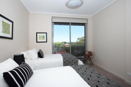 a hotel room with two beds and a window at The Junction Palais - Modern and Spacious 2BR Bondi Junction Apartment Close to Everything in Sydney