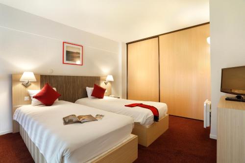 a hotel room with two beds and a flat screen tv at Vacancéole - Les Demeures Champenoises Confort in Épernay