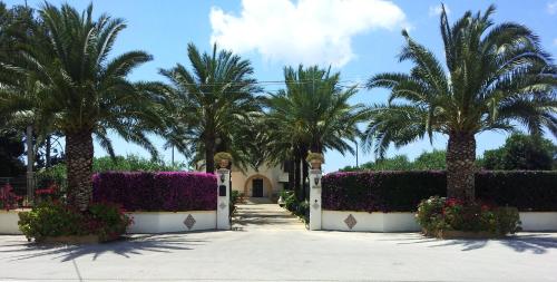 a villa with palm trees and flowers in a driveway at Villa Sogno Charme E Relax in Marinella di Selinunte
