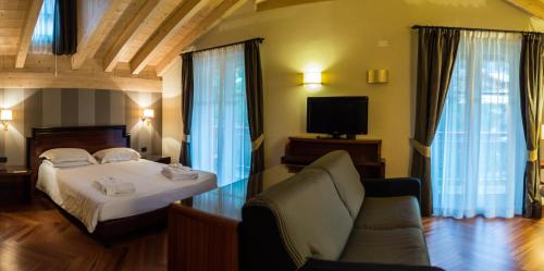 een slaapkamer met een bed, een bank en een tv bij Villa Madonna in Madonna di Campiglio