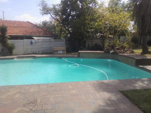 a swimming pool with a hose in a yard at Fourways Johannesburg Hostel in Johannesburg