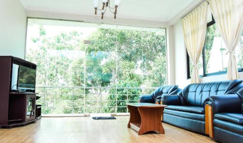 a living room with a blue couch and a large window at Kandy View Hotel in Kandy