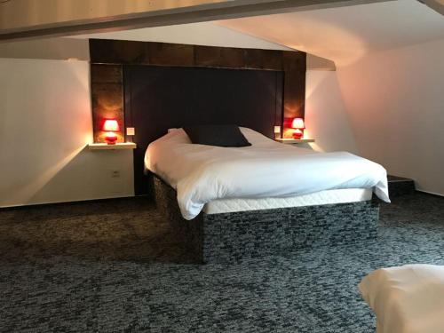 a bedroom with a large bed with white sheets and two lamps at La Demeure des 2 Trésors in La Bresse