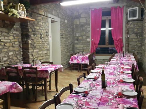 a row of tables in a room with pink tablecloths at Agriturismo Prato degli Angeli in Sassoleone