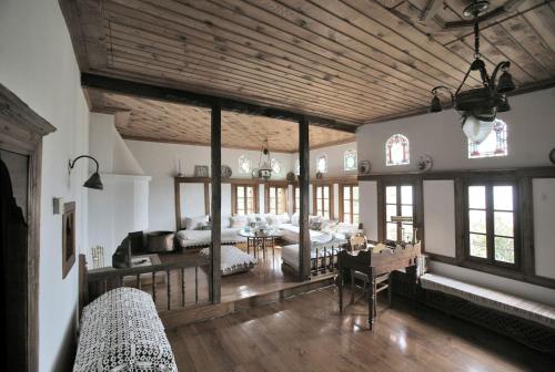 een grote woonkamer met houten plafonds en een eetkamer bij Pelion Belvedere - THE MANSION in Vizitsa