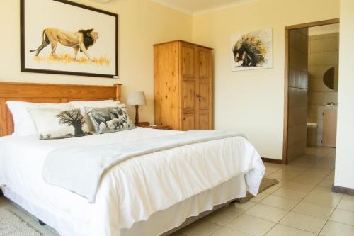 a bedroom with a large white bed and a bathroom at Cuckoo Ridge Country Retreat in Hazyview