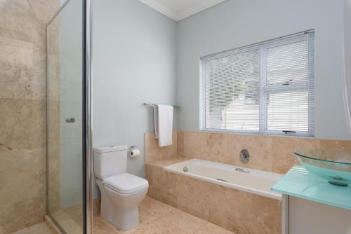 a bathroom with a toilet and a tub and a sink at 61 on Camps Bay in Cape Town