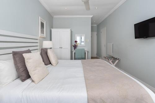a large white bed in a room with a tv at 61 on Camps Bay in Cape Town