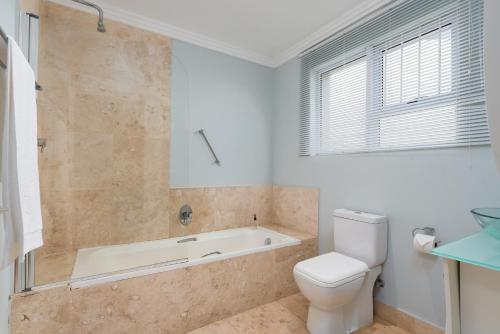 a bathroom with a bath tub and a toilet at 61 on Camps Bay in Cape Town