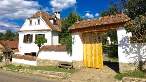 a white house with a yellow door in front of it at Count Kálnoky's Transylvanian Guesthouses in Micloşoara