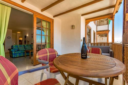 Una botella de vino sentada en una mesa de madera en una habitación en First line beach front 2 bedroom apartment Los Gigantes, en Santiago del Teide