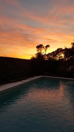 a swimming pool with a sunset in the background at Villa Chamarel in Carcès