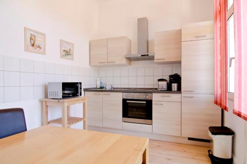 ゾーリンゲンにあるApartmondo Ferienwohnungen Solingenのキッチン(白い家電製品、木製テーブル付)