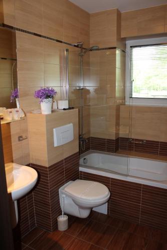 a bathroom with a toilet and a tub and a sink at Aviator Hotel Restauracja & SPA in Pabianice