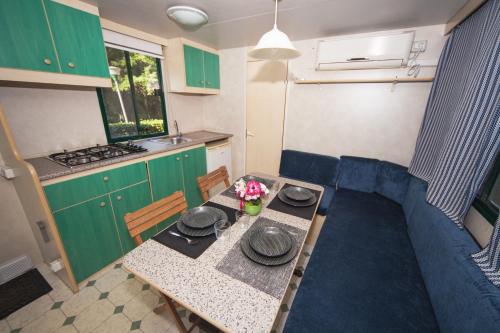 a small kitchen with a table and a kitchen with green cabinets at Toscana Holiday Village in Montopoli in Val dʼArno