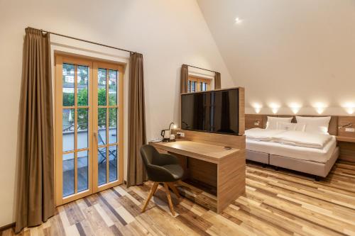 1 dormitorio con escritorio, TV y cama en Hotelmyhome en Hornberg