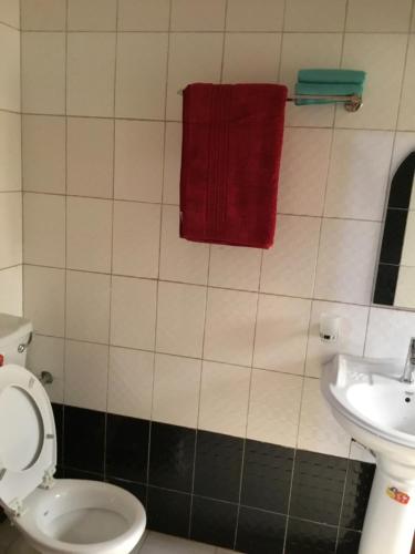 a bathroom with a toilet and a red towel on the wall at Motel Tuku Masindi in Masindi