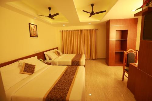 a hotel room with two beds and a television at The Crescent Suites in Ernakulam