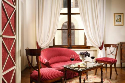 a room with a red chair and a table and a window at Palazzo Niccolini al Duomo Residenza D'Epoca in Florence