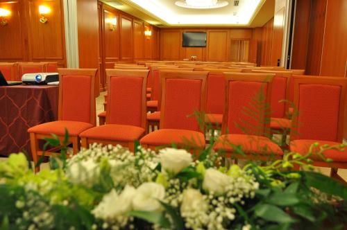 a conference room with red chairs and flowers at Domus Hotel in Bagnoli del Trigno