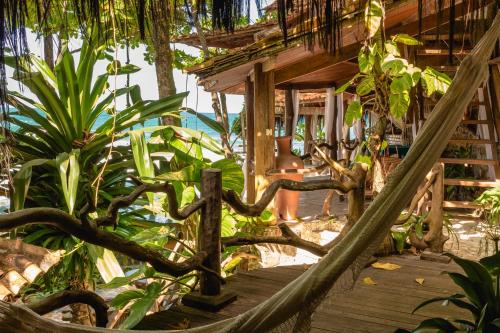 a hammock in front of a house with plants at Pousada Sage Point in Itacaré