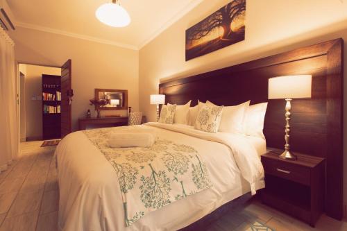 a bedroom with a large bed with a wooden headboard at Three Olives Guesthouse in Centurion