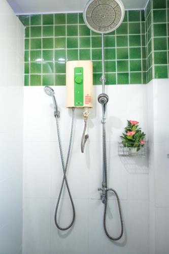 a shower in a bathroom with green tiles at Plus Hostel Ayutthaya in Phra Nakhon Si Ayutthaya