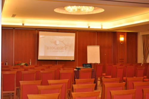 a lecture hall with red chairs and a projection screen at Domus Hotel in Bagnoli del Trigno