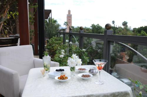 uma mesa branca com comida e bebidas numa varanda em Riad Wow em Marrakech