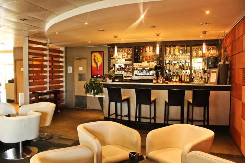 un bar en un restaurante con sillas y una barra en Hotel L'Hotan en Portet-sur-Garonne